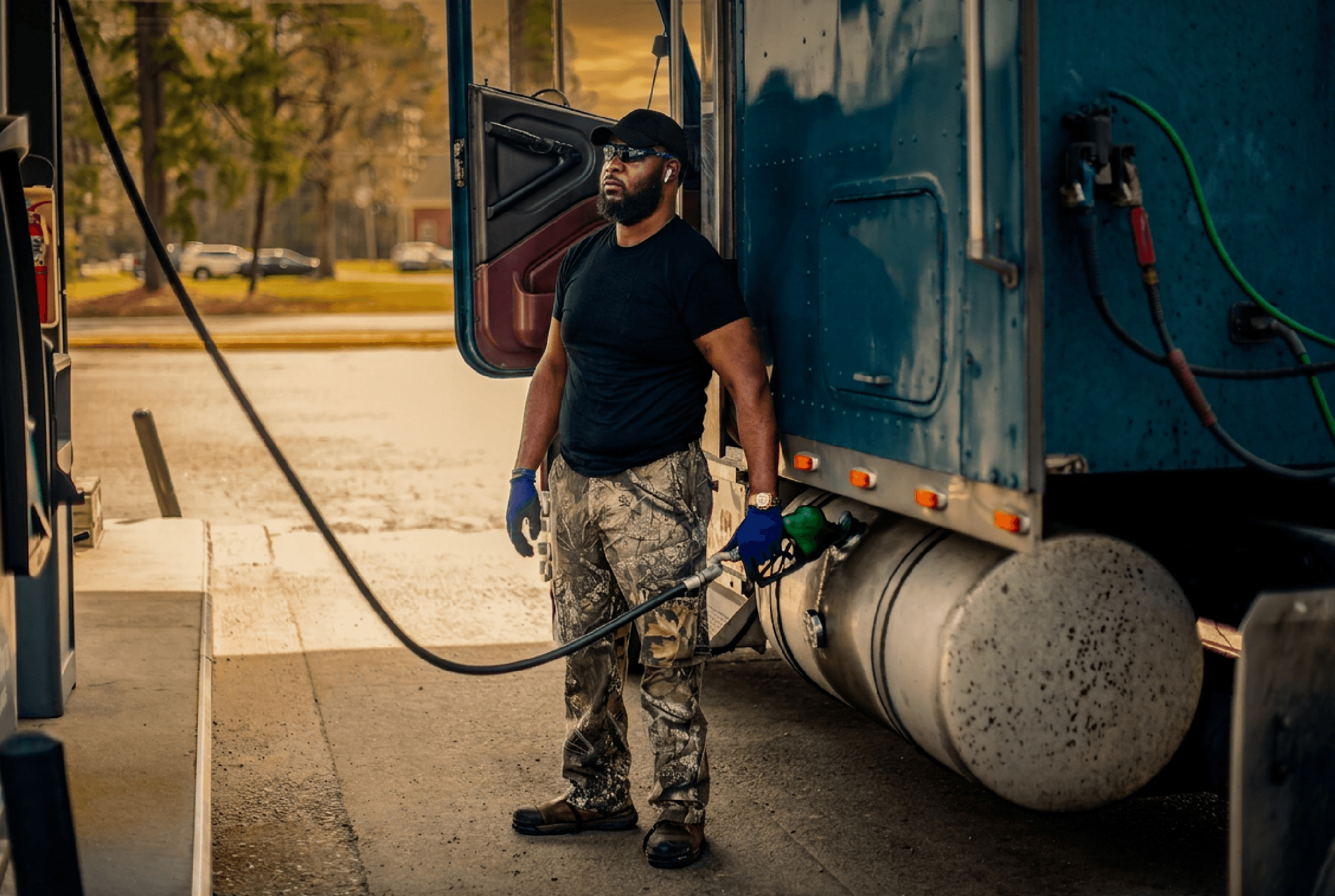 Bearded truck driver fueling up with diesel at a truck stop