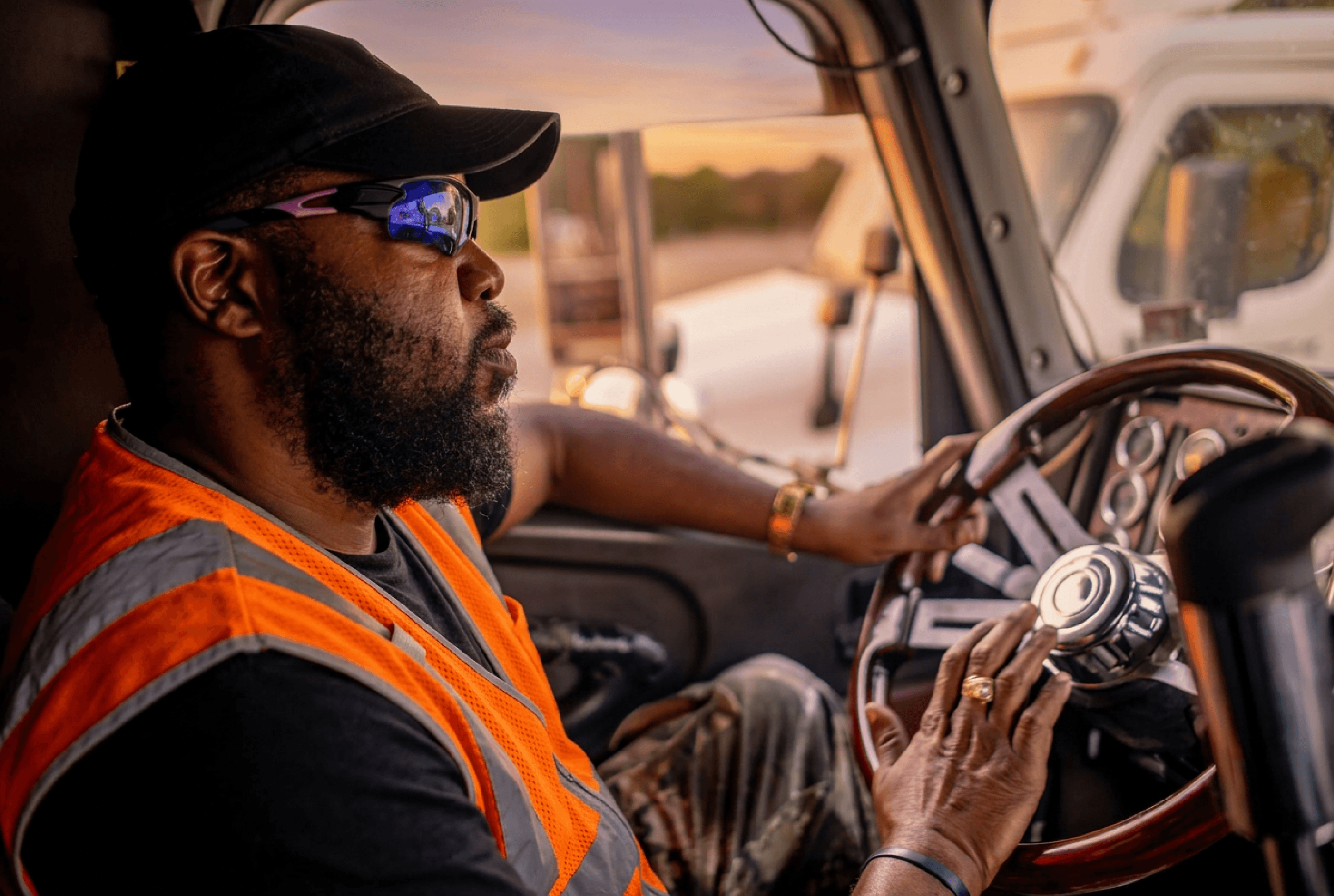 Man in an orange vest passing by a white semi-truck